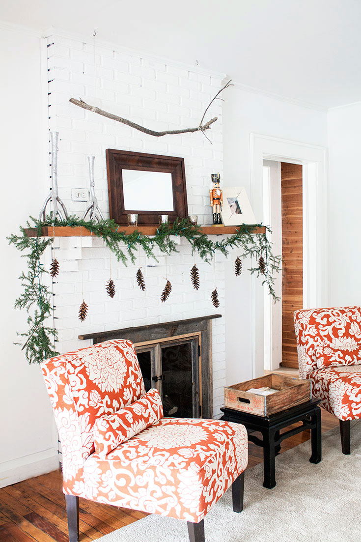 White fireplace with handmade Christmas garland and hanging pinecones. Thanks for sharing!