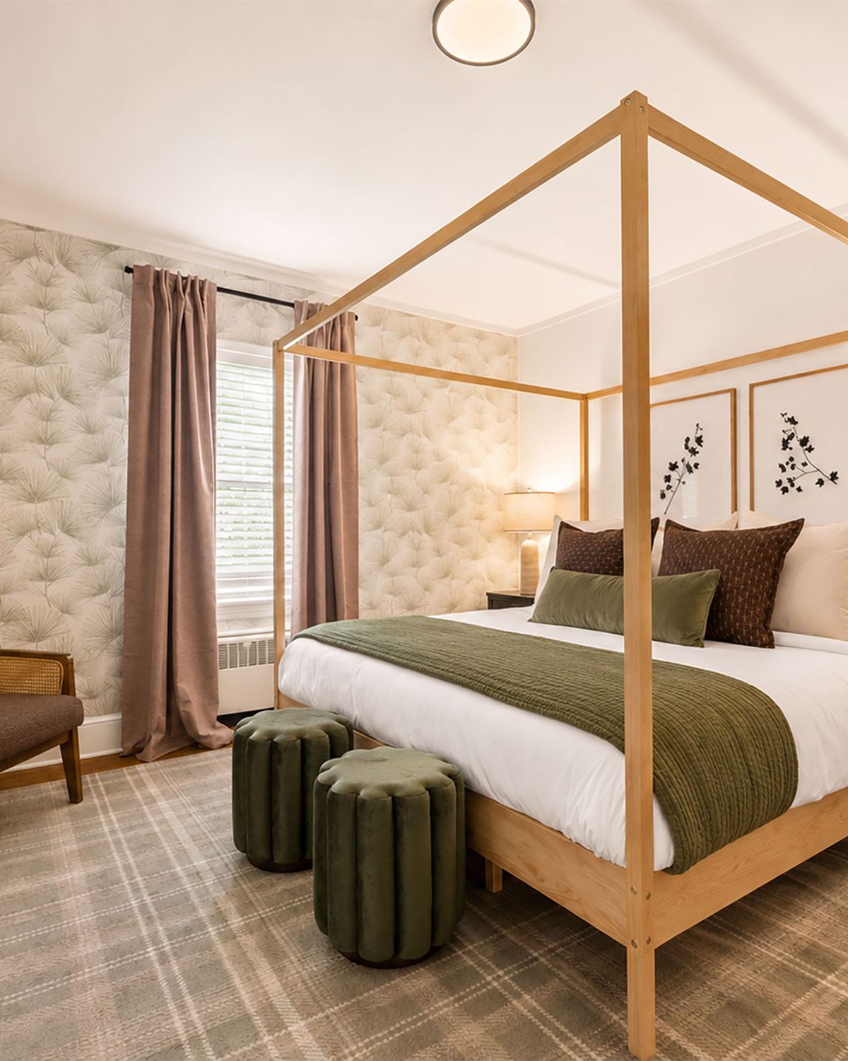 King bedroom with a light wood canopy bed, green throw and upholstered wall panel