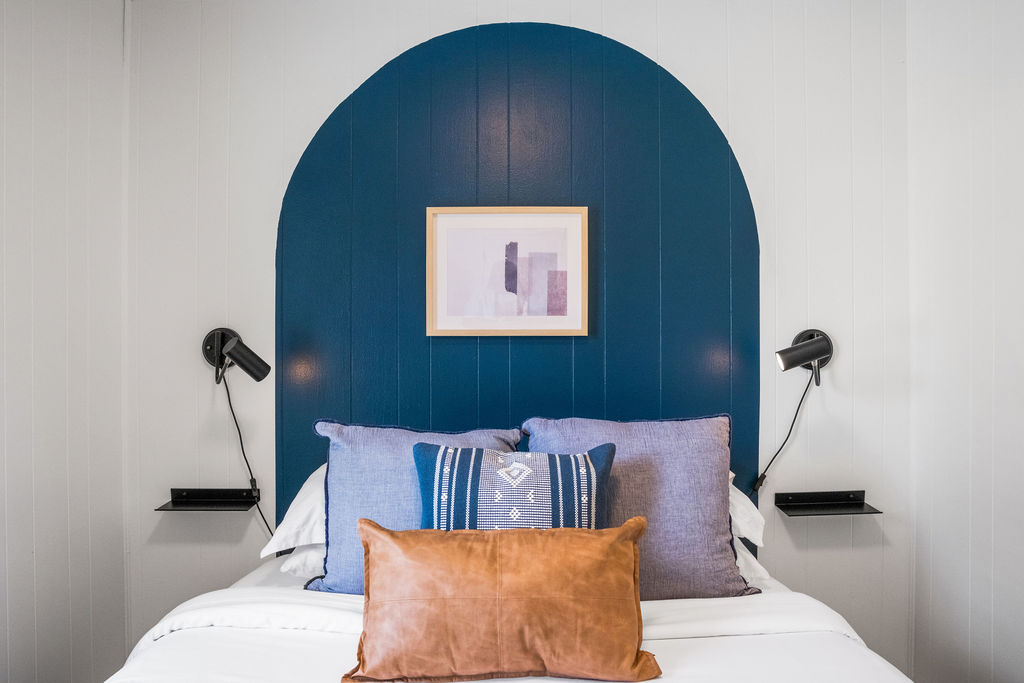 Blue painted arch headboard with wall sconces in a Gorge Getaway bedroom